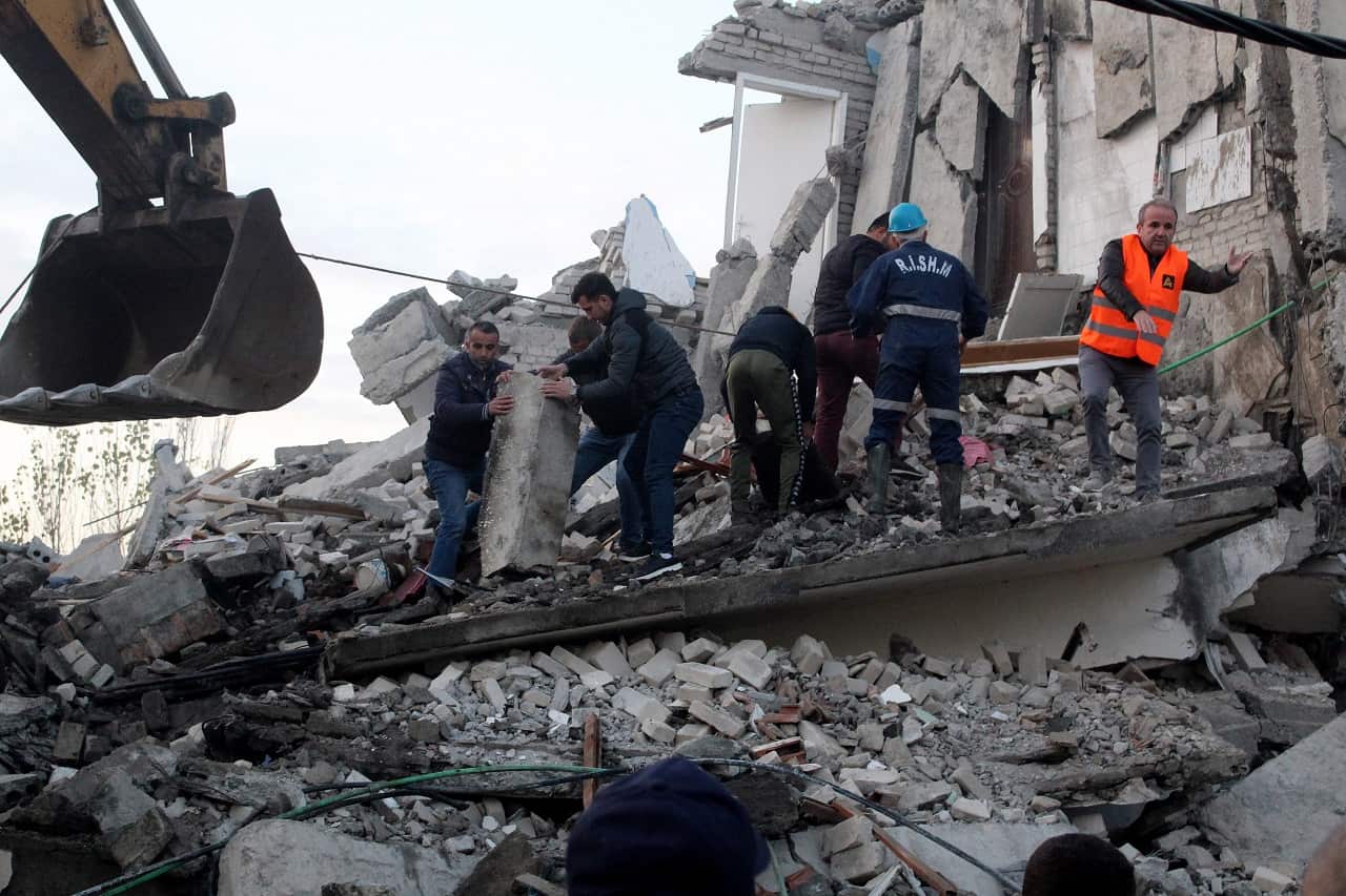 People search for survivors in the rubble of a building in Thumane.