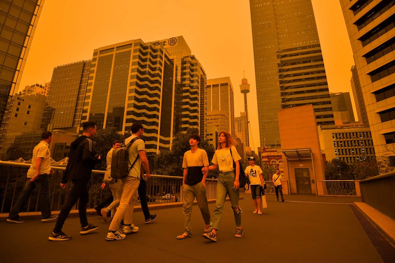 Pedestrians walk towards Darling Harbour as smoke haze blankets Sydney on Friday.