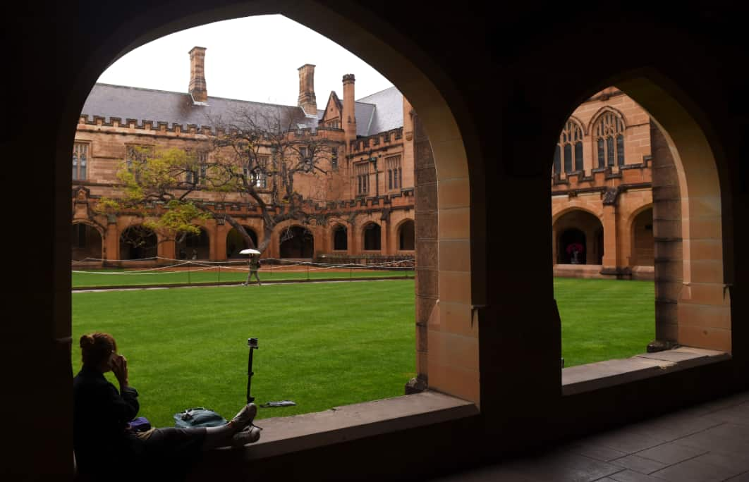 A student sits next to the quadrangle at the University of Sydney, 