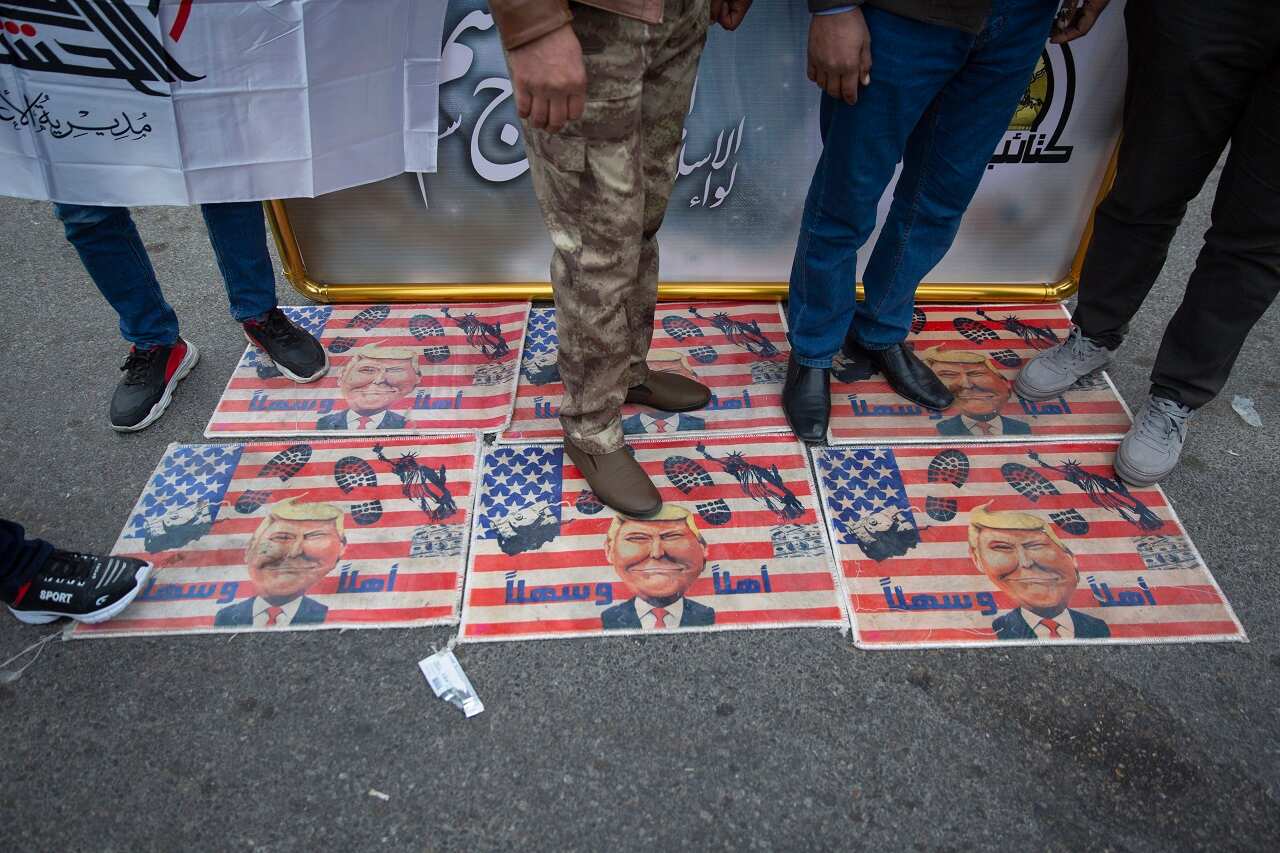 Mourners step over a US flags with pictures of President Trump.