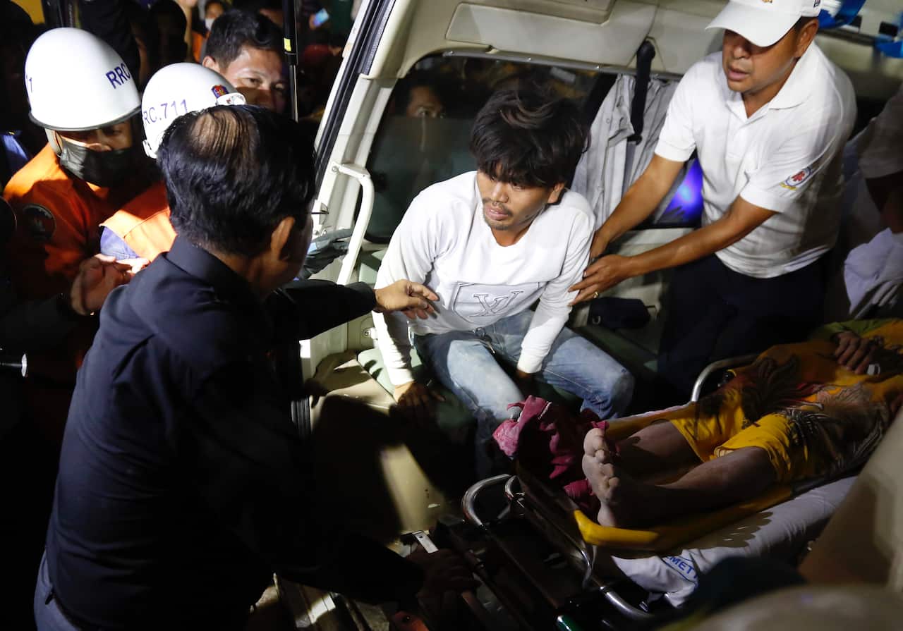 Cambodian Prime Minister Hun Sen (L, back to camera) talks to an unidentified injured worker (C) in an ambulance at the site of a collapsed building.