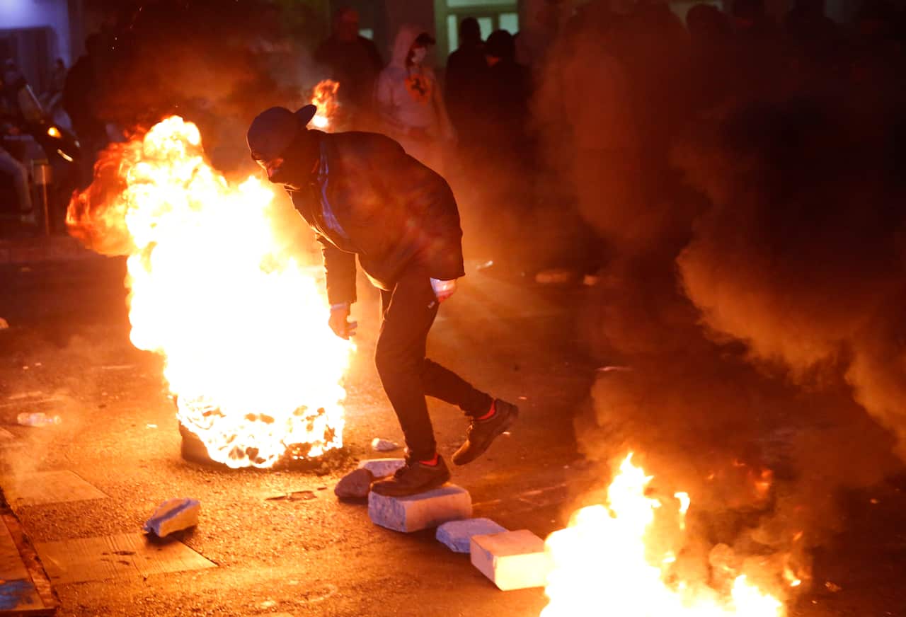 An anti-government protester passes between burning tires during ongoing protests against the country's financial woes, in Beirut, Lebanon.