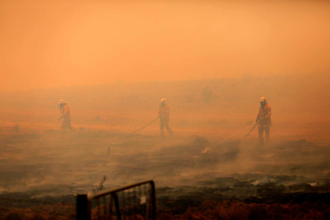 NSW RFS crews extinguish a fire that crossed the Monaro Highway, four kilometres north of Bredbo.