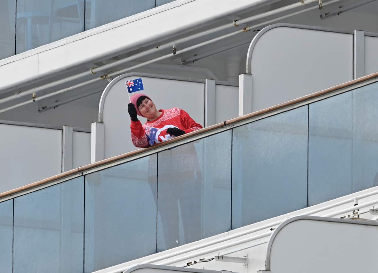 A passenger waves the Australian flag from her balcony onboard the Princess Diamond.