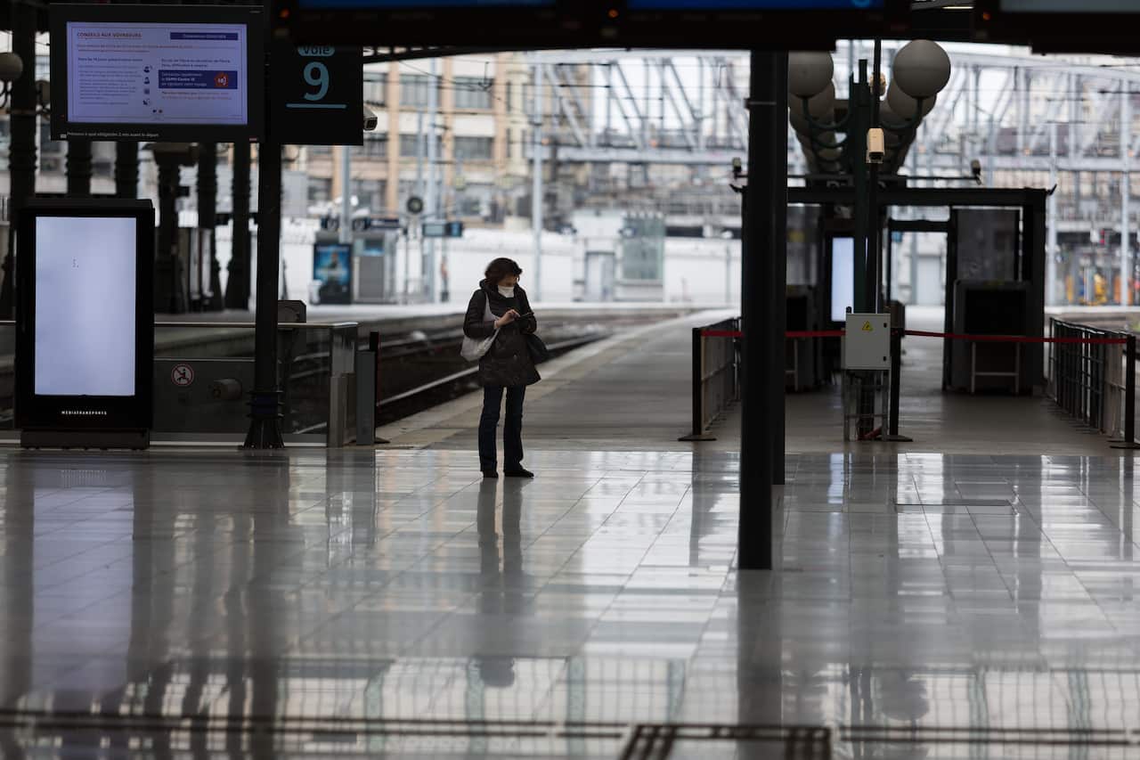 A woman wearing a face mask stands in a desolate Gare du Nord train station in Paris, France on Saturday.