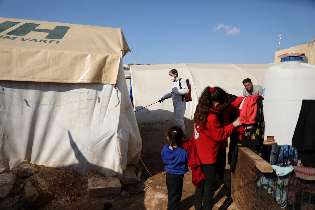 A volunteer from Violet Organization sprays disinfectants as precautionary against coronavirus at tents and public facilities in a camp in Idlib, Syria