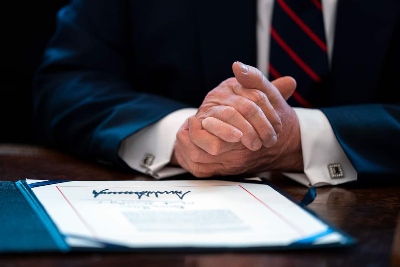 President Donald Trump finishes signing the coronavirus stimulus relief package in the Oval Office at the White House.