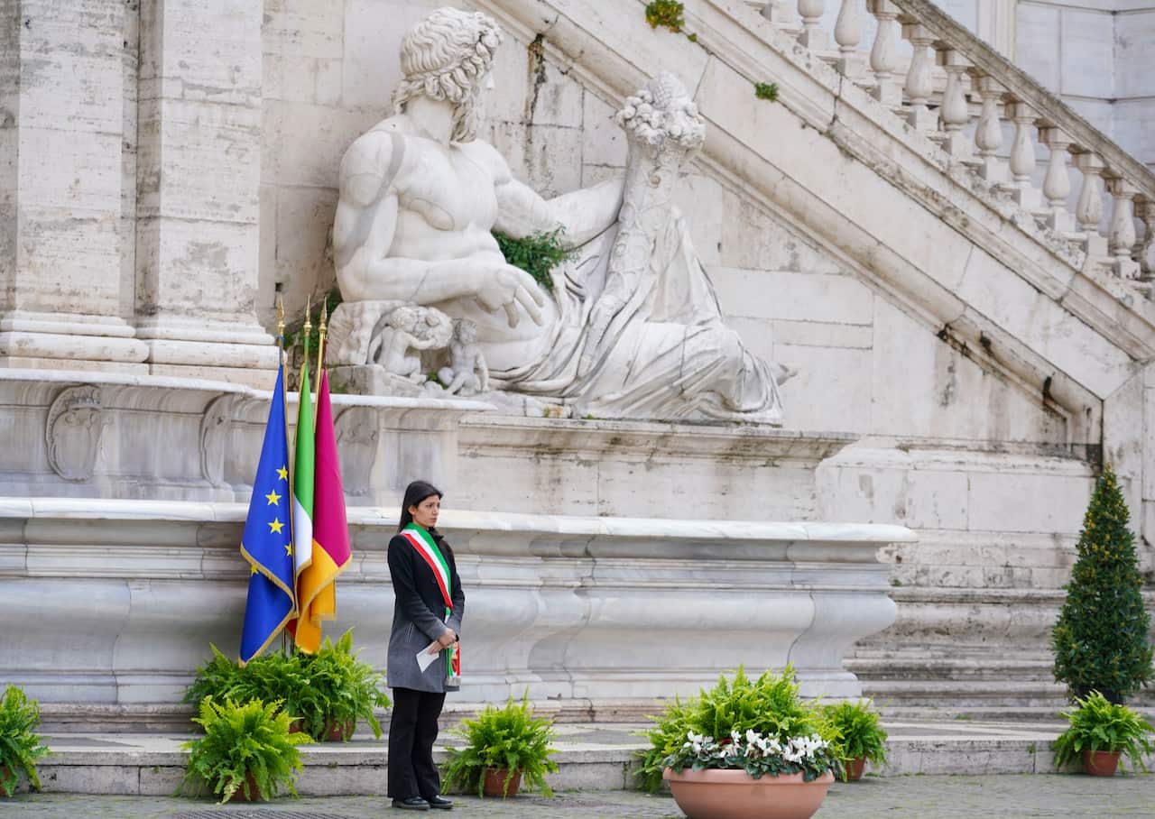 Rome's Mayor Virginia Raggi stands in front of flags at half-staff during the minute of silence.