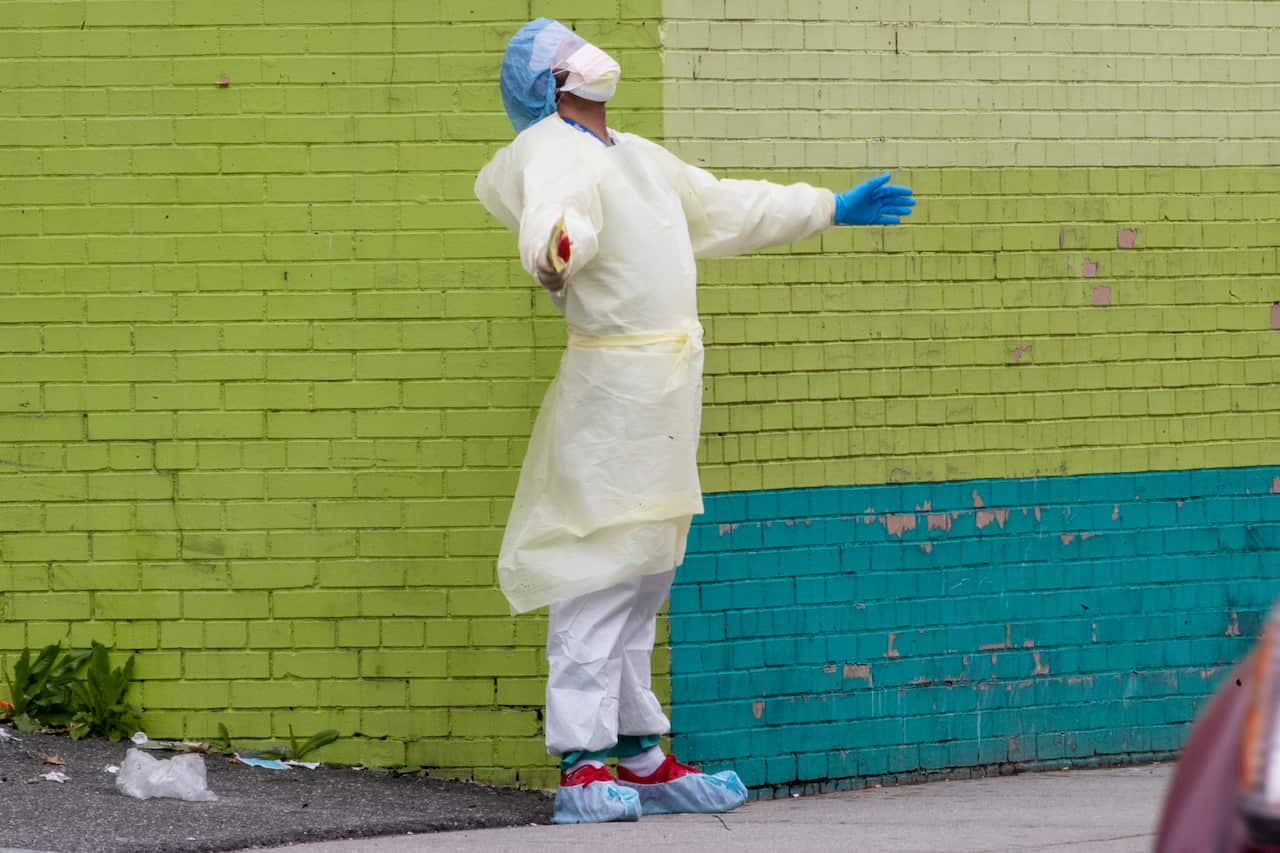 A health worker from a New York Hospital reacts after stepping outside of the emergency room, in the Queens borough of New York.