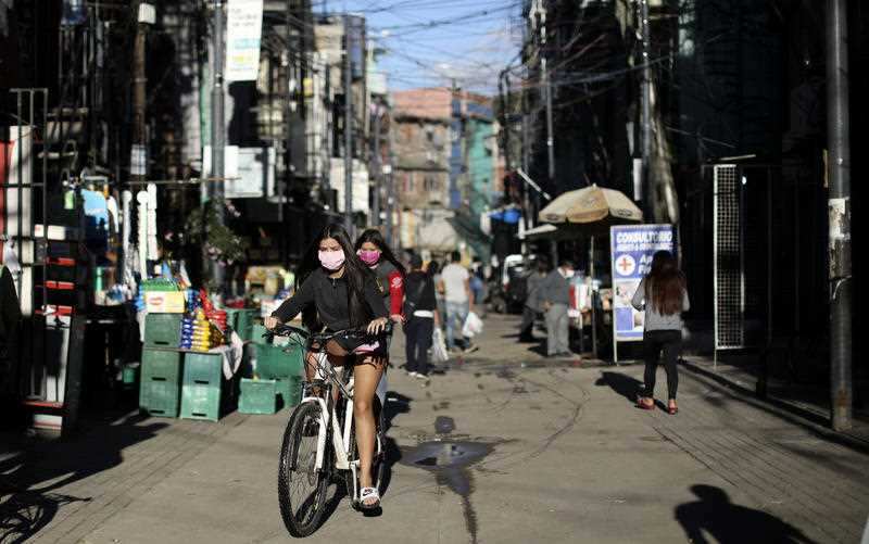 Girls ride on a bicycle at the Villa 31 slum