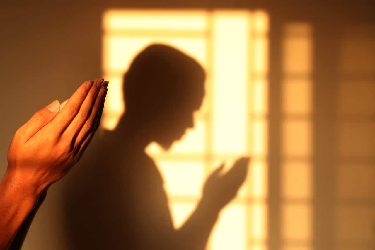 Silhouette of a Muslim man offering prayers at home during the holy month of Ramada amid coronavirus crisis.