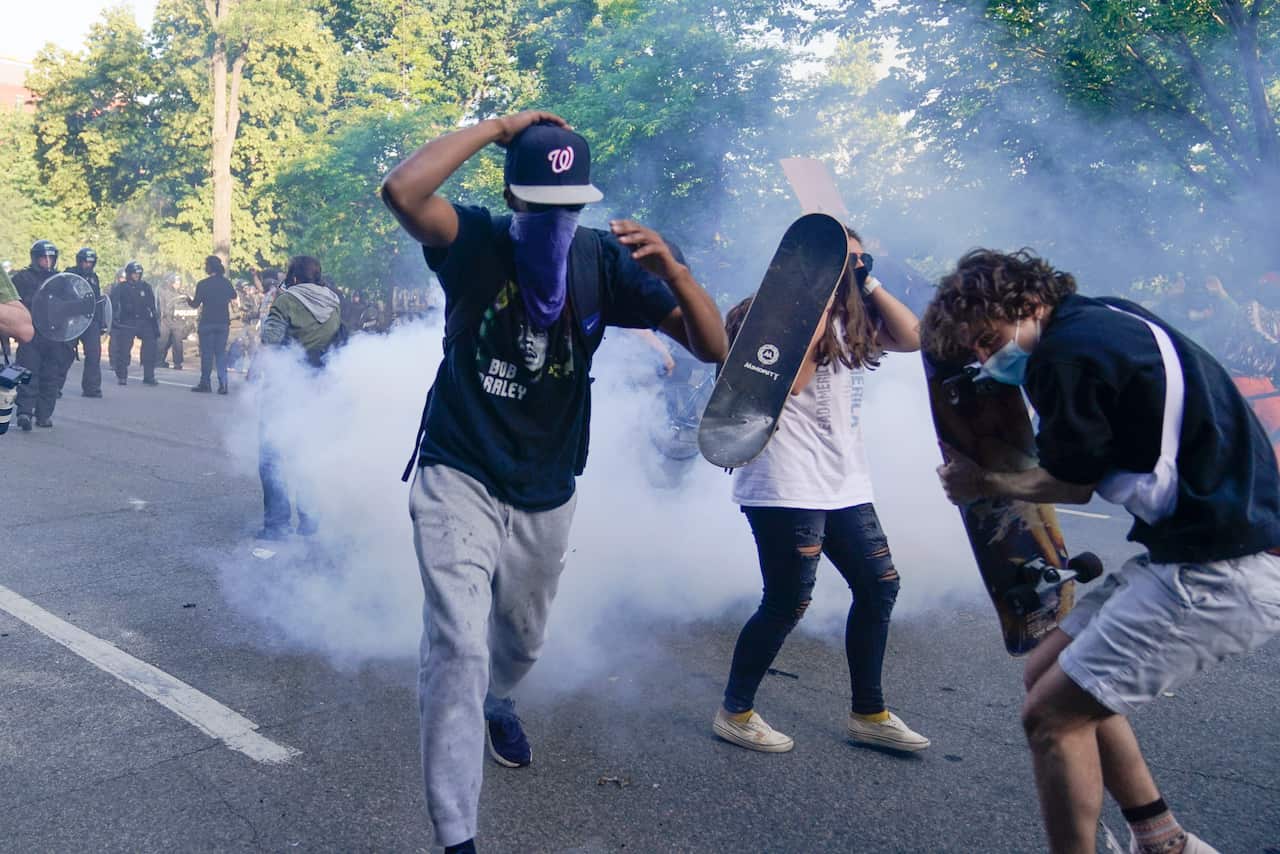 Demonstrators run from tear gas used by police to clear the street near the White House in Washington.