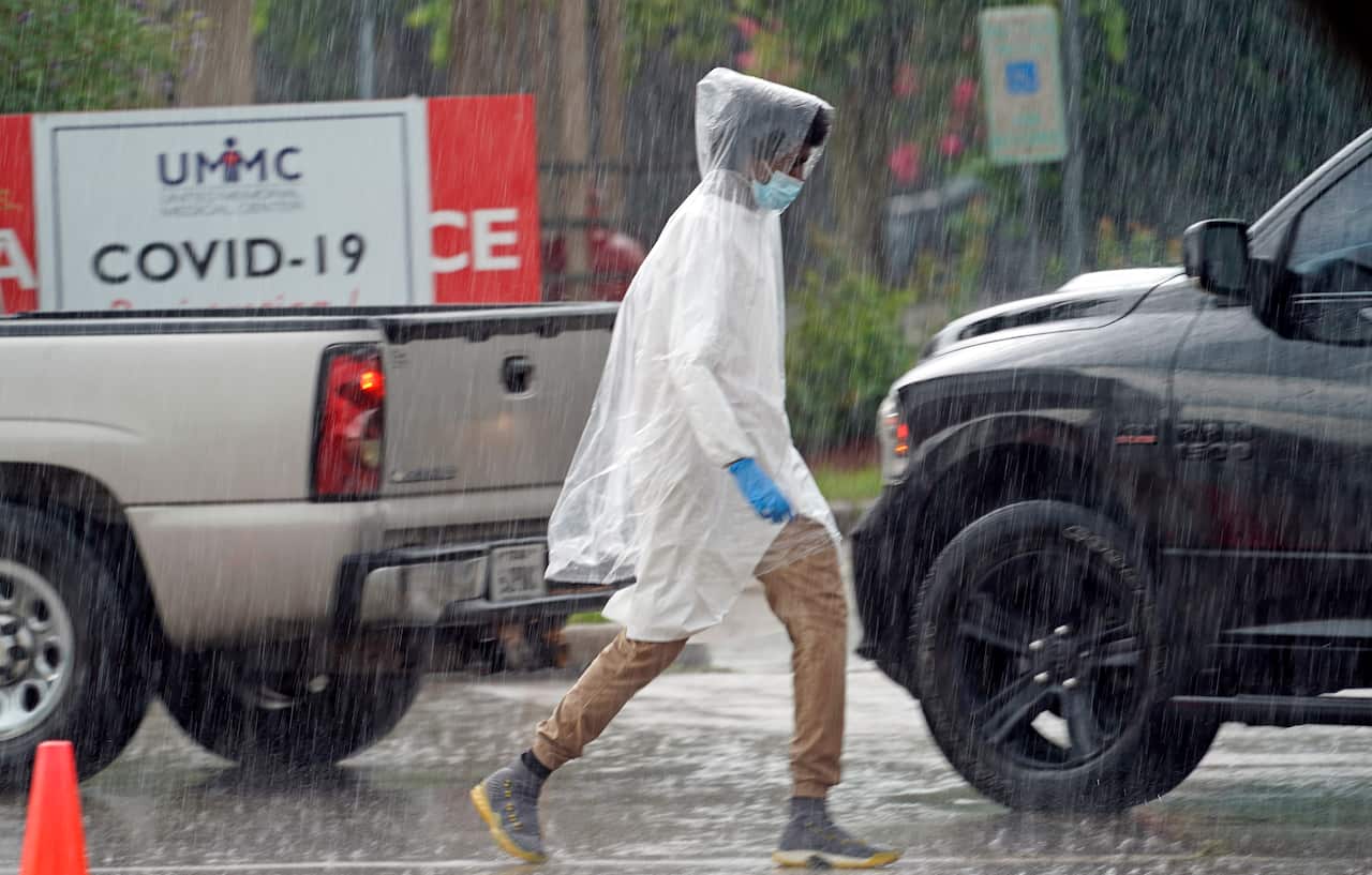 A healthcare worker walks through the rain at a United Memorial Medical Center COVID-19 testing site in Houston, Texas.