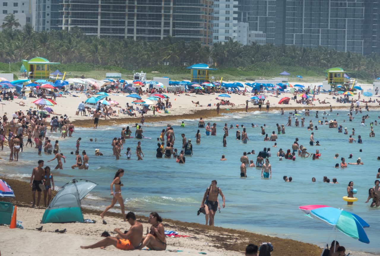 Hundreds of people enjoy a warm day at the beach in Miami Beach, Florida.