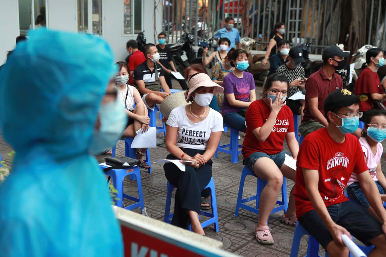 People wait in line for a COVID-19 test in Hanoi.