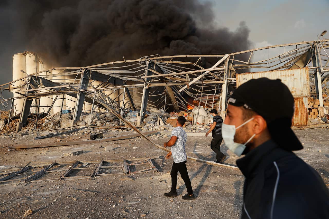 Lebanese port workers walk at the explosion scene that hit the seaport of Beirut, Lebanon, Tuesday, 4 August, 2020.