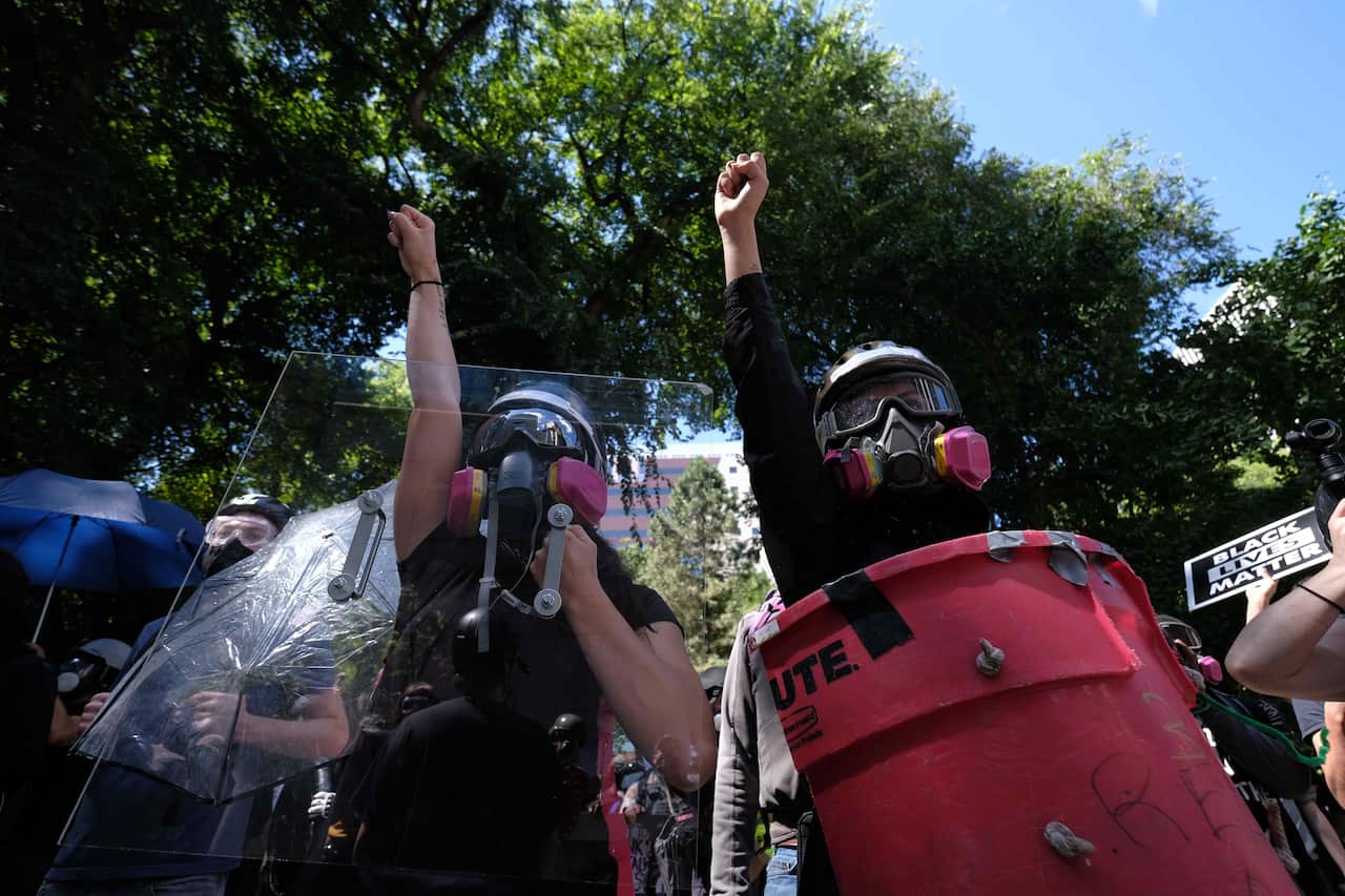 Black Lives Matter protesters stand with their fists raised against Trump supporters outside the Justice Center in Portland