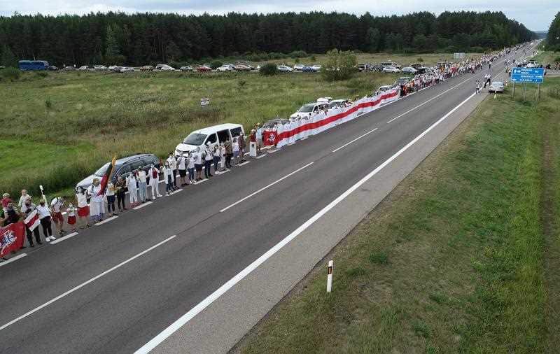 People hold hands as they participate in a human chain from Vilnius to the Belarusian border