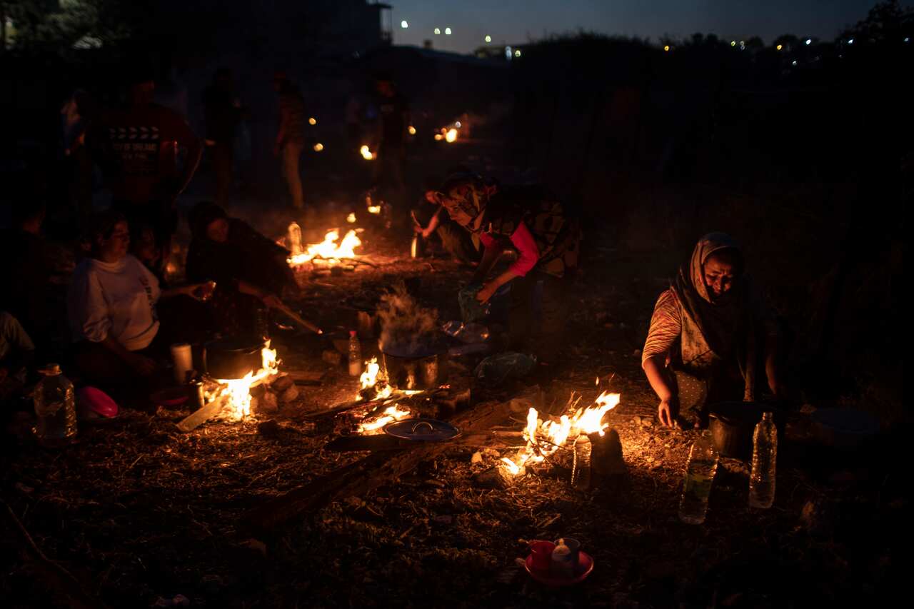 Refugees and migrants cook on makeshift fires near an abandoned factory in the island of Lesbos, Greece, on 11 September.