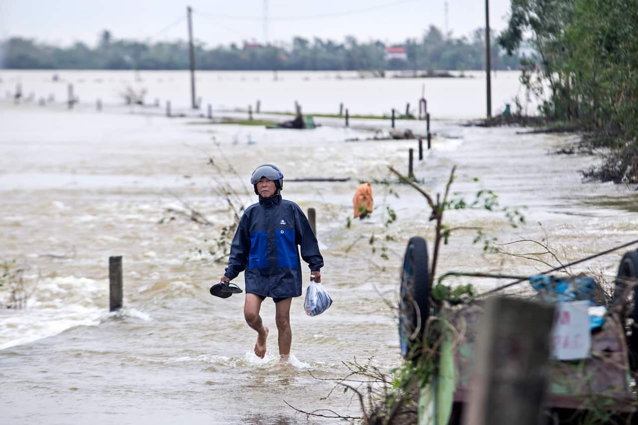 A man walking through floodwater to a pickup point for relief packages in Quang An Commune, Thua Thien Hue, Vietnam, 20 October 2020