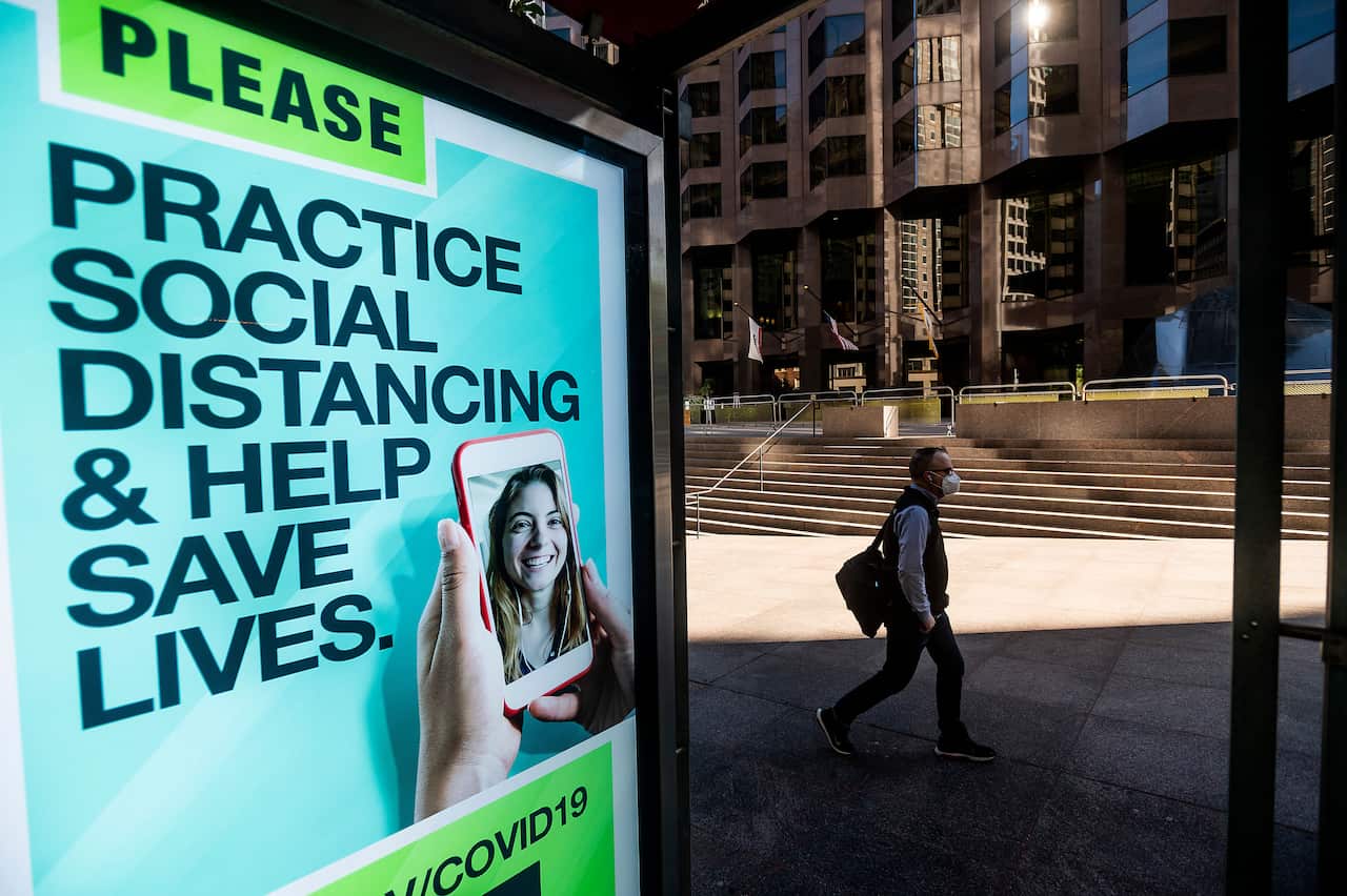 A man passes a COVID-19 public service notice in San Francisco's financial district on Wednesday, Oct. 21, 2020.