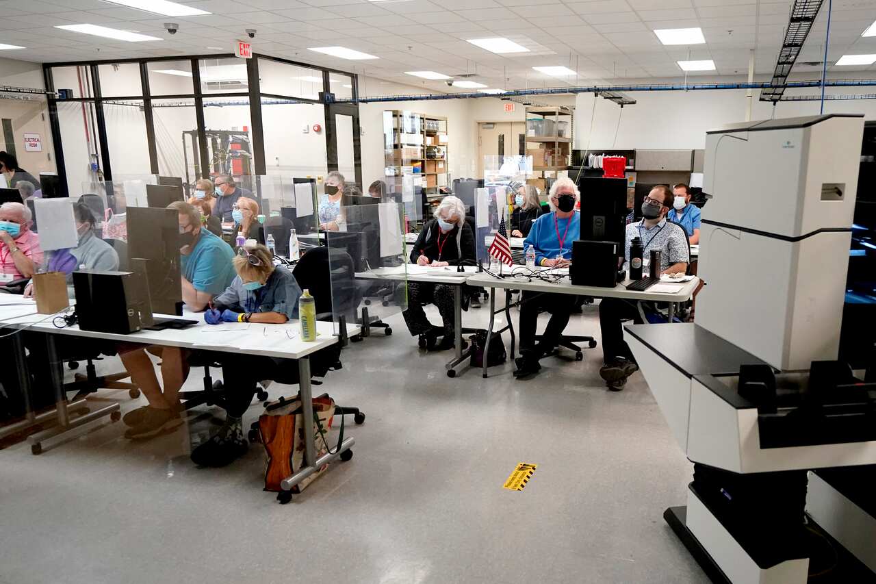 Maricopa County elections officials and observers watch as ballots are tallied.