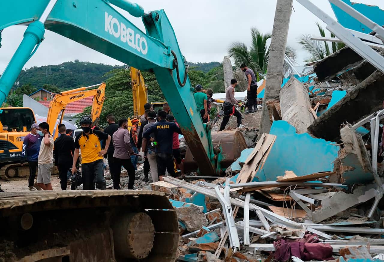 Residents inspect an earthquake-damaged buildings in Mamuju, West Sulawesi, Indonesia, Friday, Jan. 15, 2021.