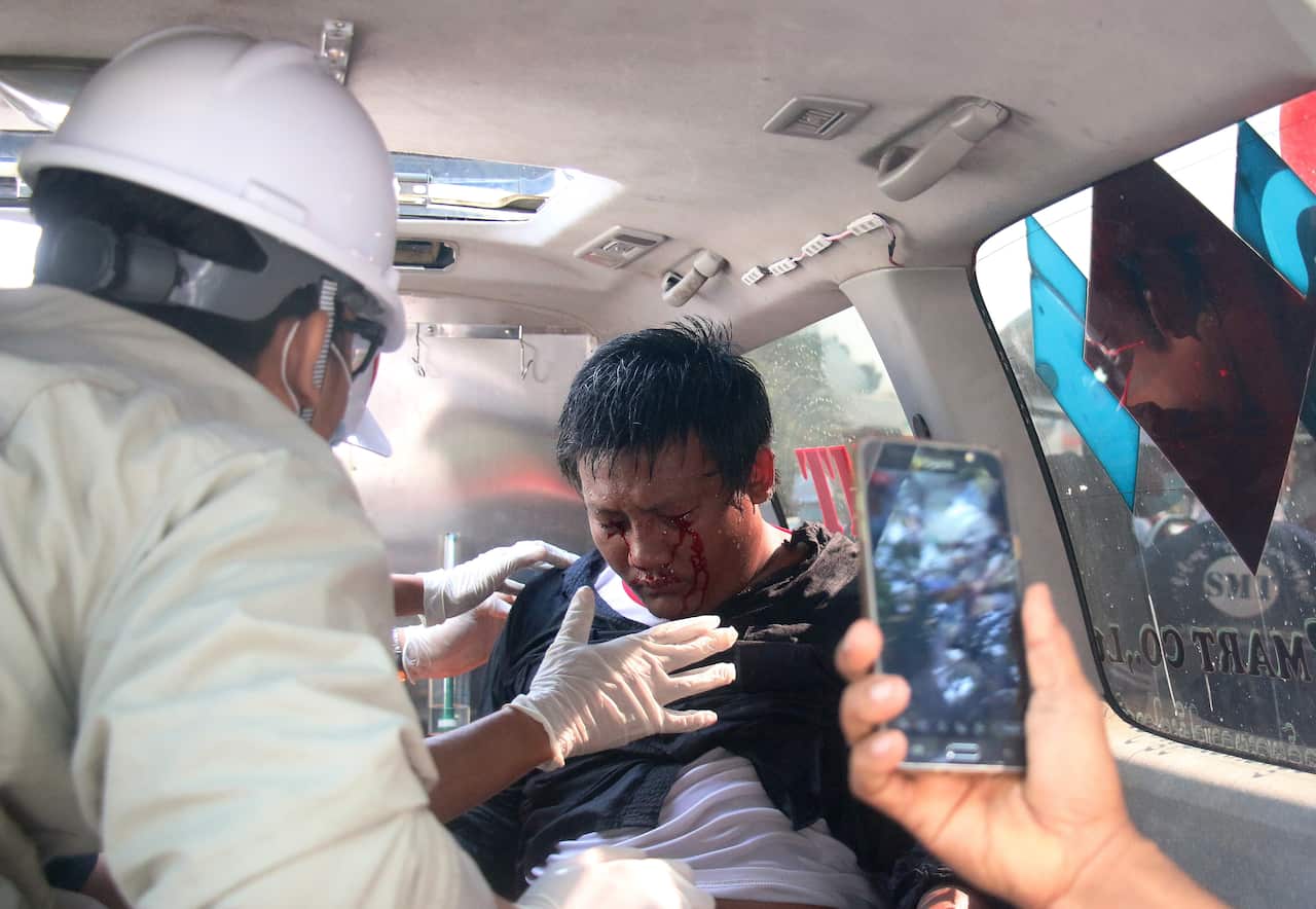 A demonstrator is tended by medics in an ambulance after police fired water cannon on demonstrators during a protest against the military coup, in Naypyitaw.