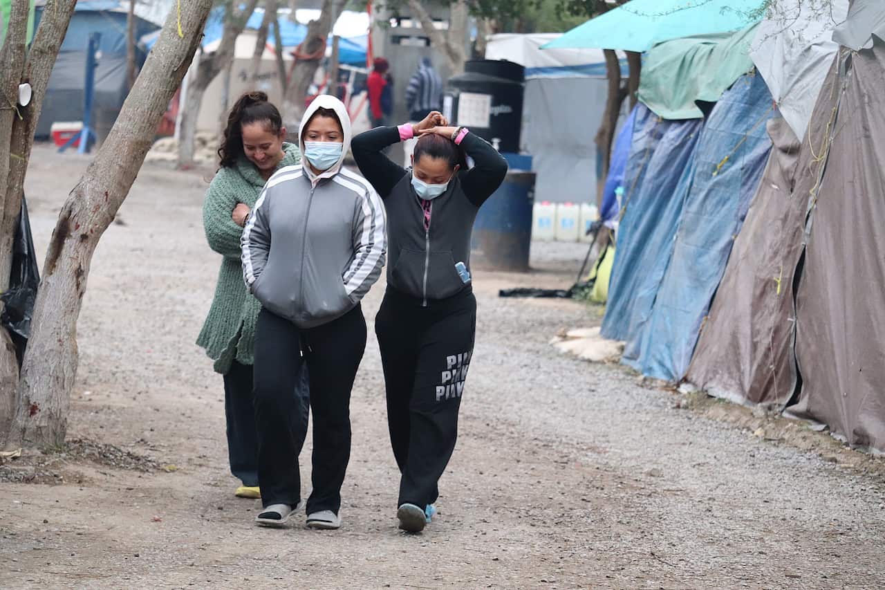 Migrant women walk through a camp located on the banks of the Rio Bravo, in the city of Matamoros, Mexico, 12 February 2021.