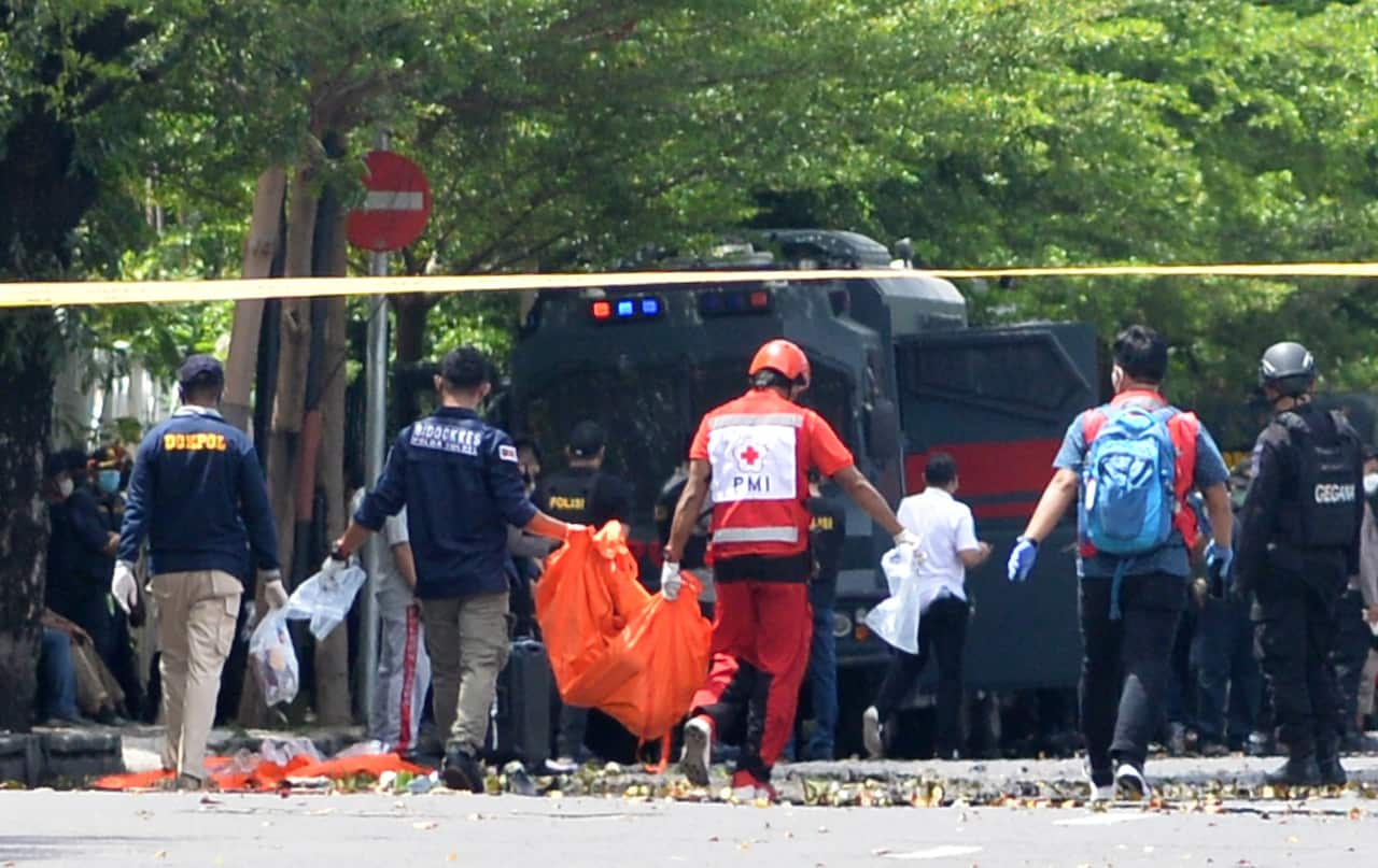 Forensic policemen carry a body bag in front of the Sacred Heart of Jesus Cathedral in the aftermath of an explosion, in Makassar, Indonesia on 28 March 2021.