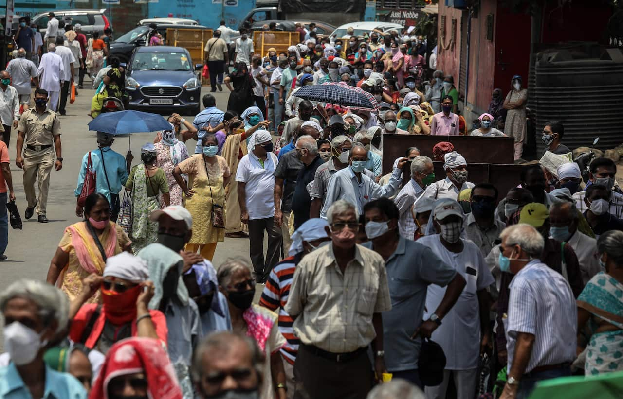 People wait in queue to receive a COVID-19 vaccine shot on the roadside in Mumbai, India