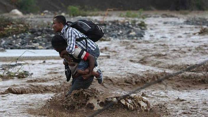 People cross a flooded street after the passing of hurricane Matthew in the country, in Grand Goave, Haiti.)