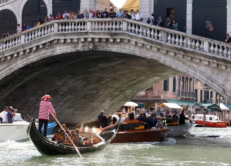 In this Sept. 26, 2014 file photo, boats pass under the famed Rialto Bridge, in Venice, Italy.