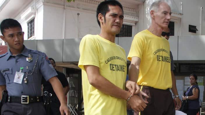 Peter Gerald Scully of Australia, right, walks in handcuffs with an unidentified detainee in 2015.