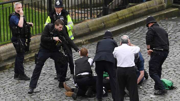 Policeman points a gun at a man on the floor in London