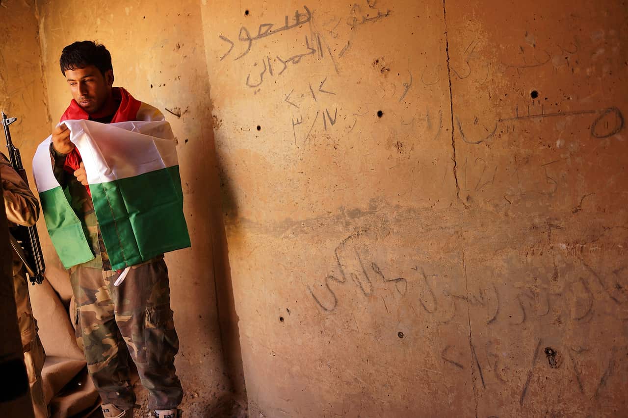 A Kurdish soldier holds a Kurdish flag at Kirkuk, Iraq