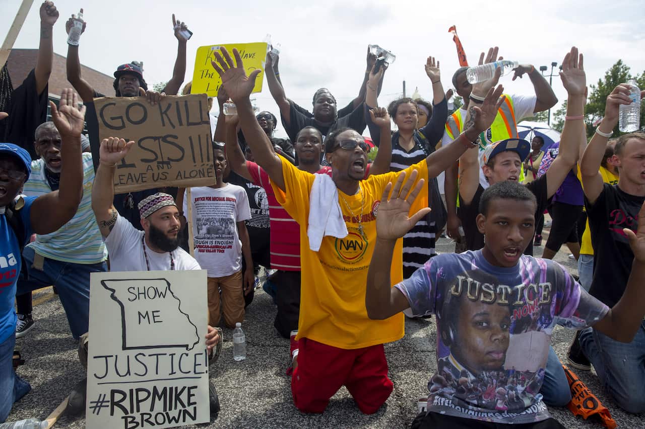 Protesters sit down in the street outside the police department during a protest over the killing of Michael Brown in Ferguson (Getty)