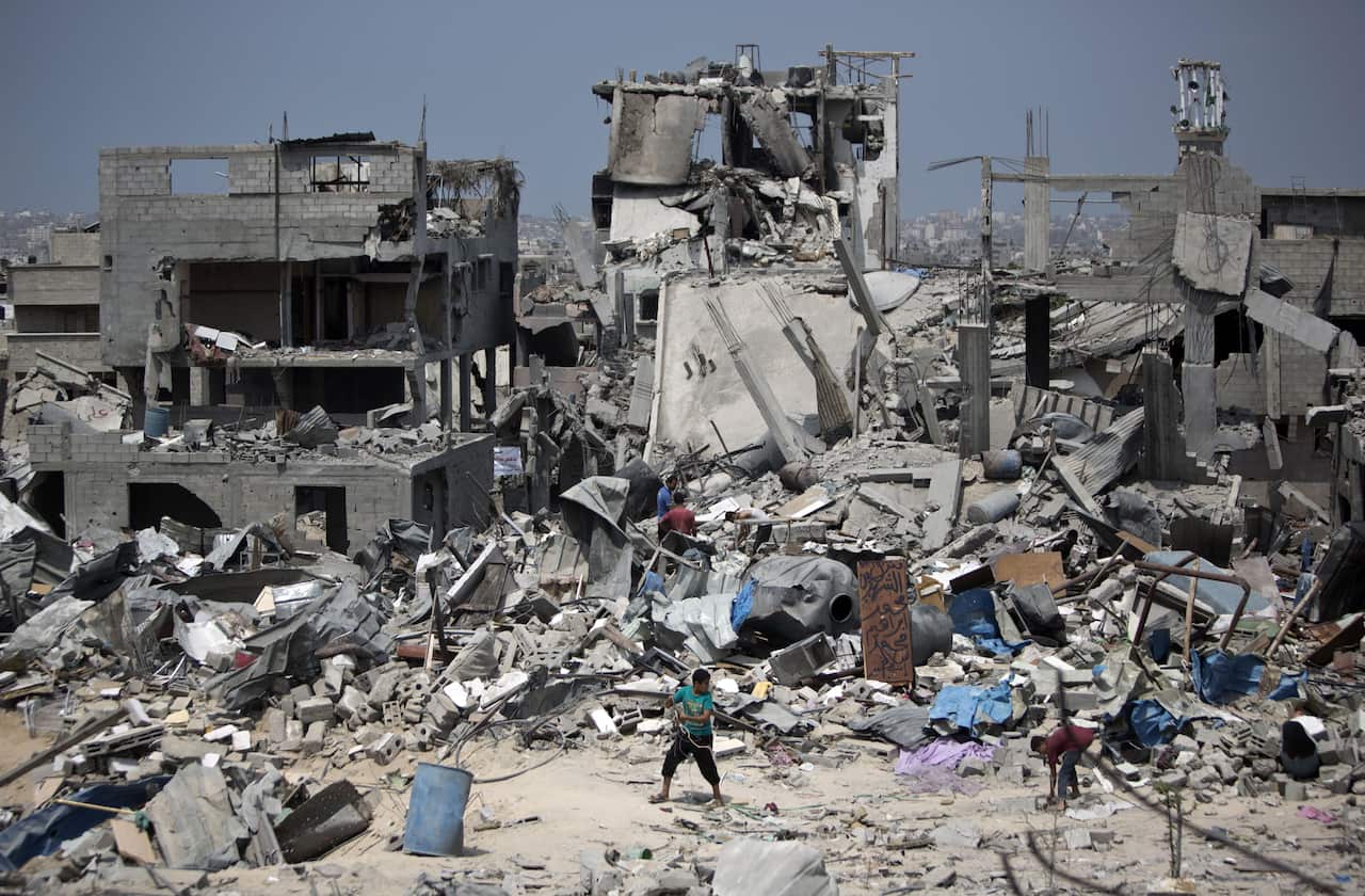 Palestinian men walk on the rubble of their destroyed houses in the Tufah neighbourhood in eastern Gaza City on August 31, 2014, following a 50-day war between Israel and Hamas militants in the Gaza Strip.