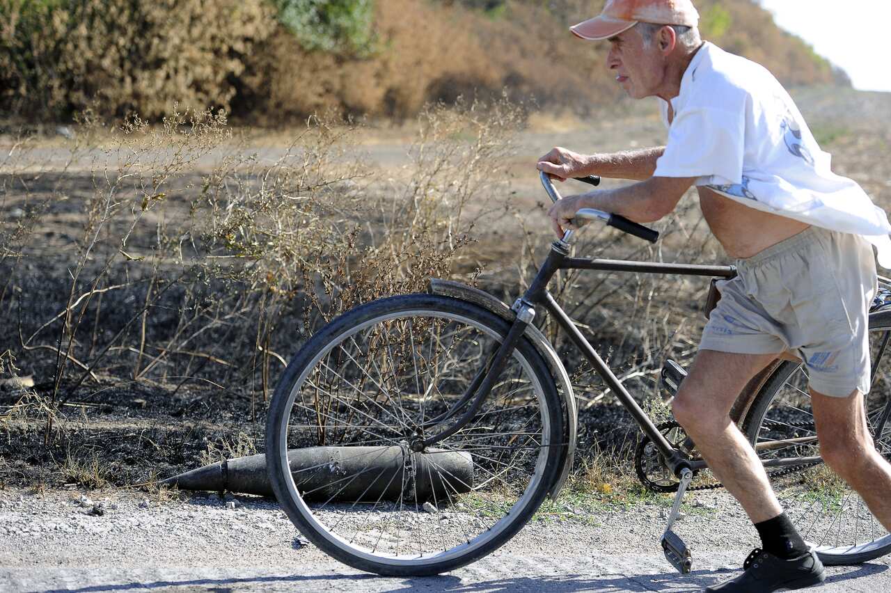 Man pushes bicycle past unexploded shell Talakovka, Ukraine.