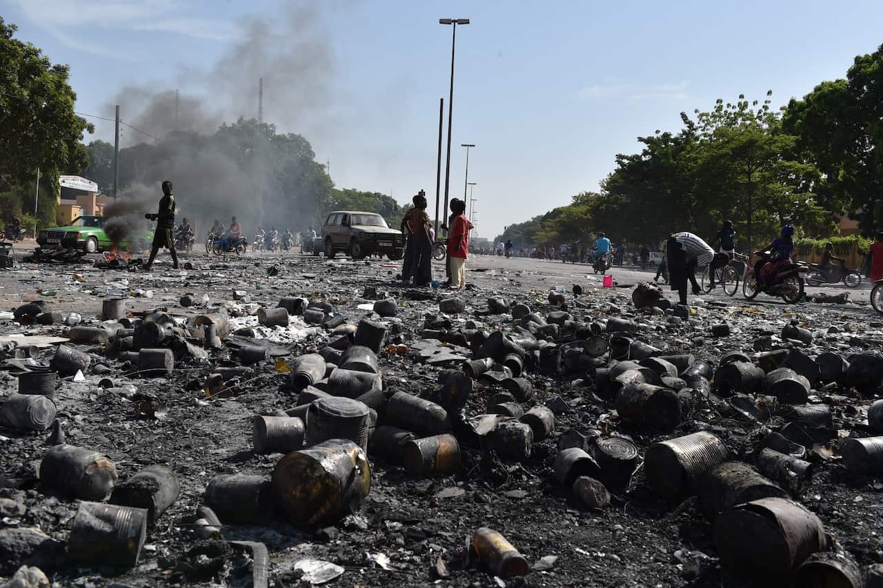 People stand on the avenue leading to the burnt parliament in Ouagadougou a day after it was stormed by protesters as lawmakers. (Getty)