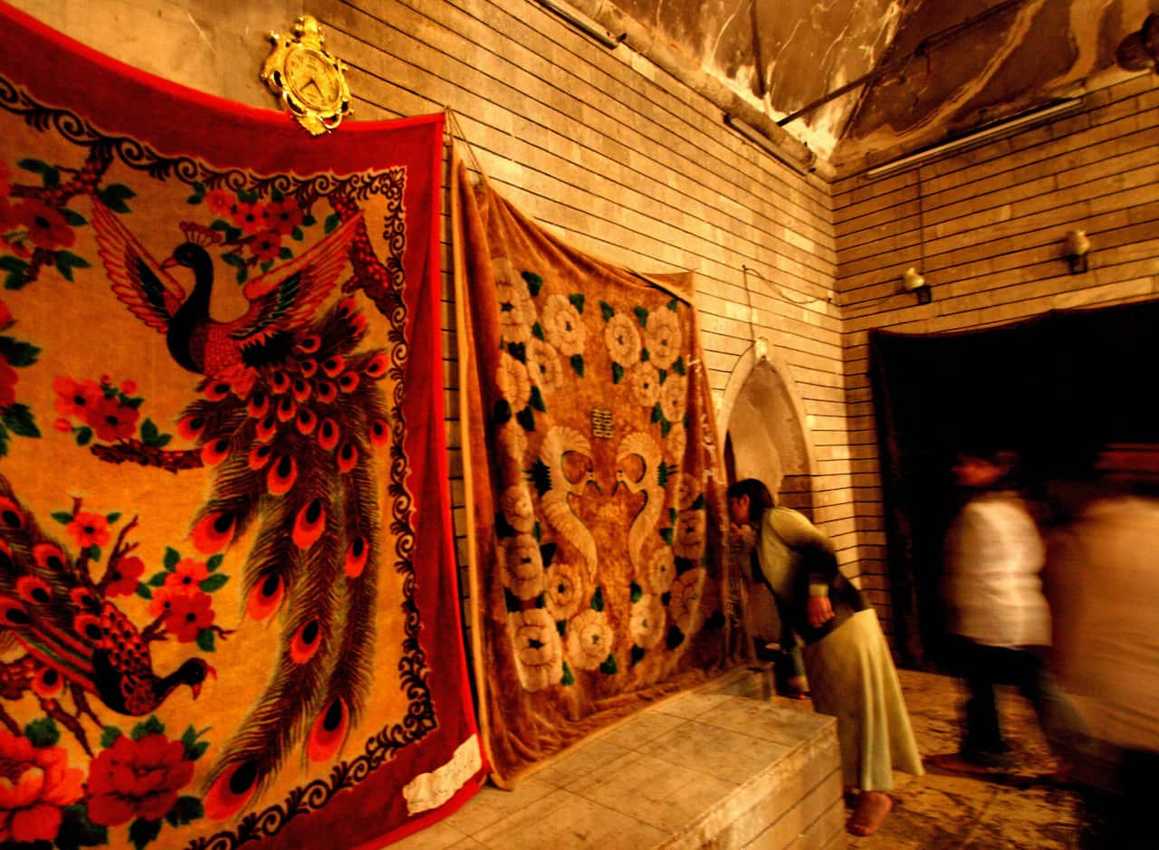 Iraqi Yazidis kiss a sacred drape representing a peacock