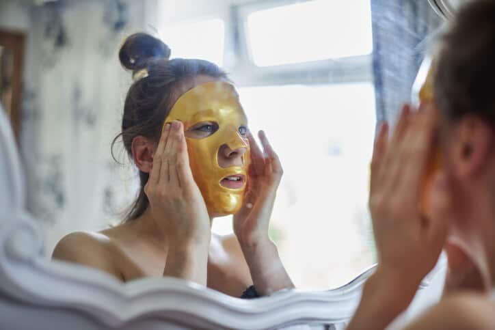 Woman looking in a mirror putting a face mask on