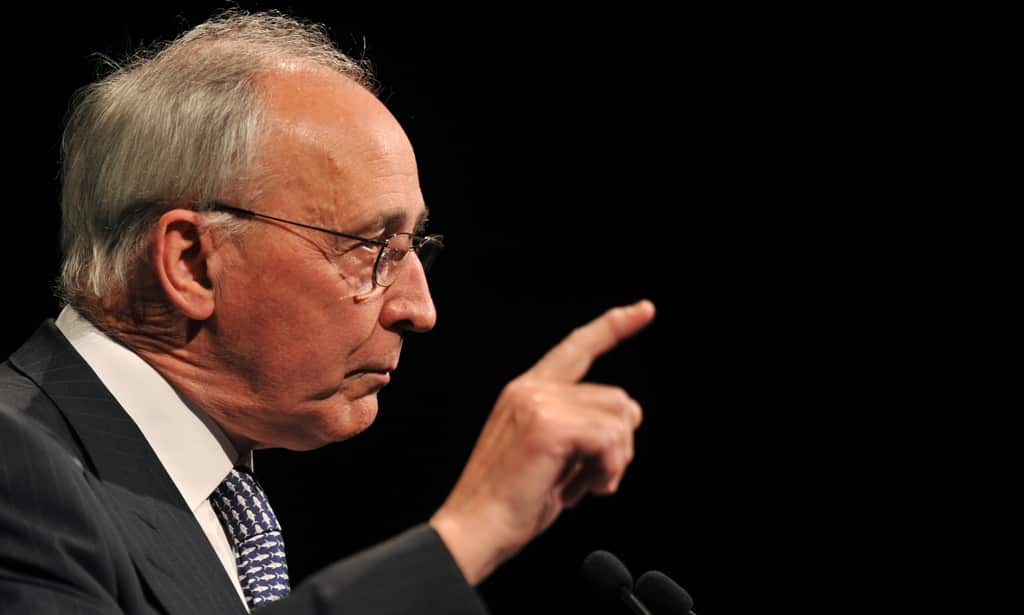 An elderly man is pointing his finger as he speaks.