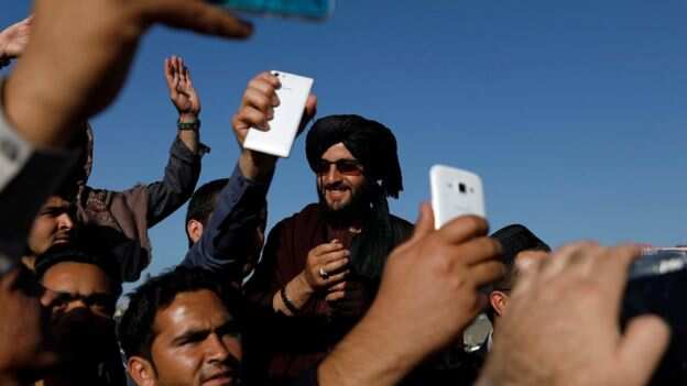 Afghans take selfies with Taliban militants in Kabul.