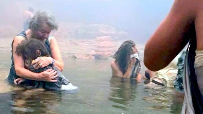 People escaping wildfires wade into the waters of the "Silver Coast" beach, Mati, Greece.