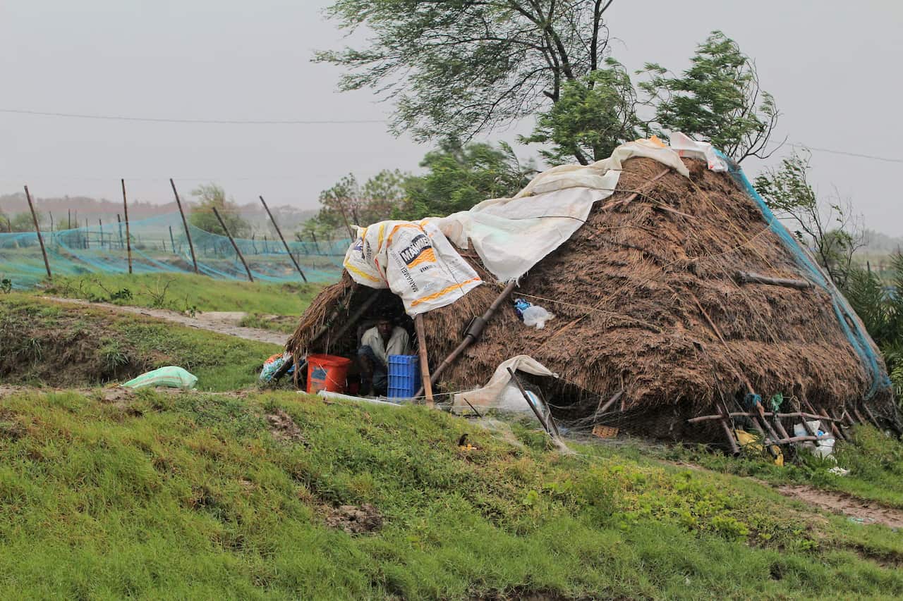 A man takes shelter from the wind and rain in eastern India (AAP)