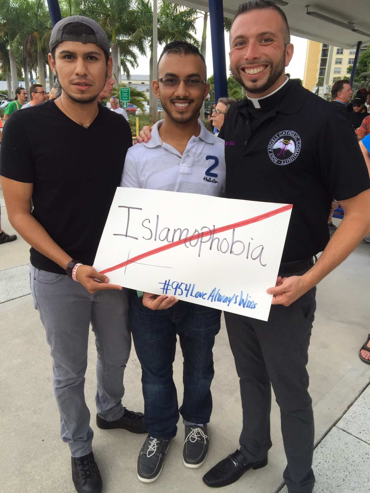 Three men holding a sign with a cross through Islamophobia