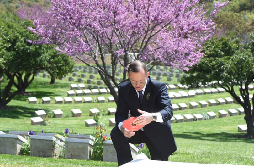  Australian Prime Minister Tony Abbott reads a paper poppy containing heart-felt messages at Shrapnel Valley Cemetery ahead of Anzac Day 