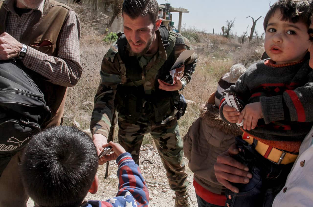 Syria's official SANA released photos of government soldiers helping the exit of a new batch of besieged civilians from Eastern Ghouta.