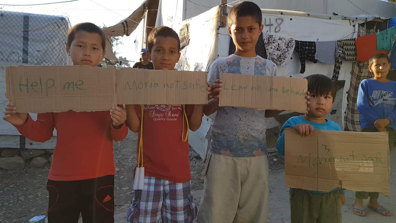 Asylum seekers hold up signs in the Moria Refugee Camp on Lesbos island, Greece.